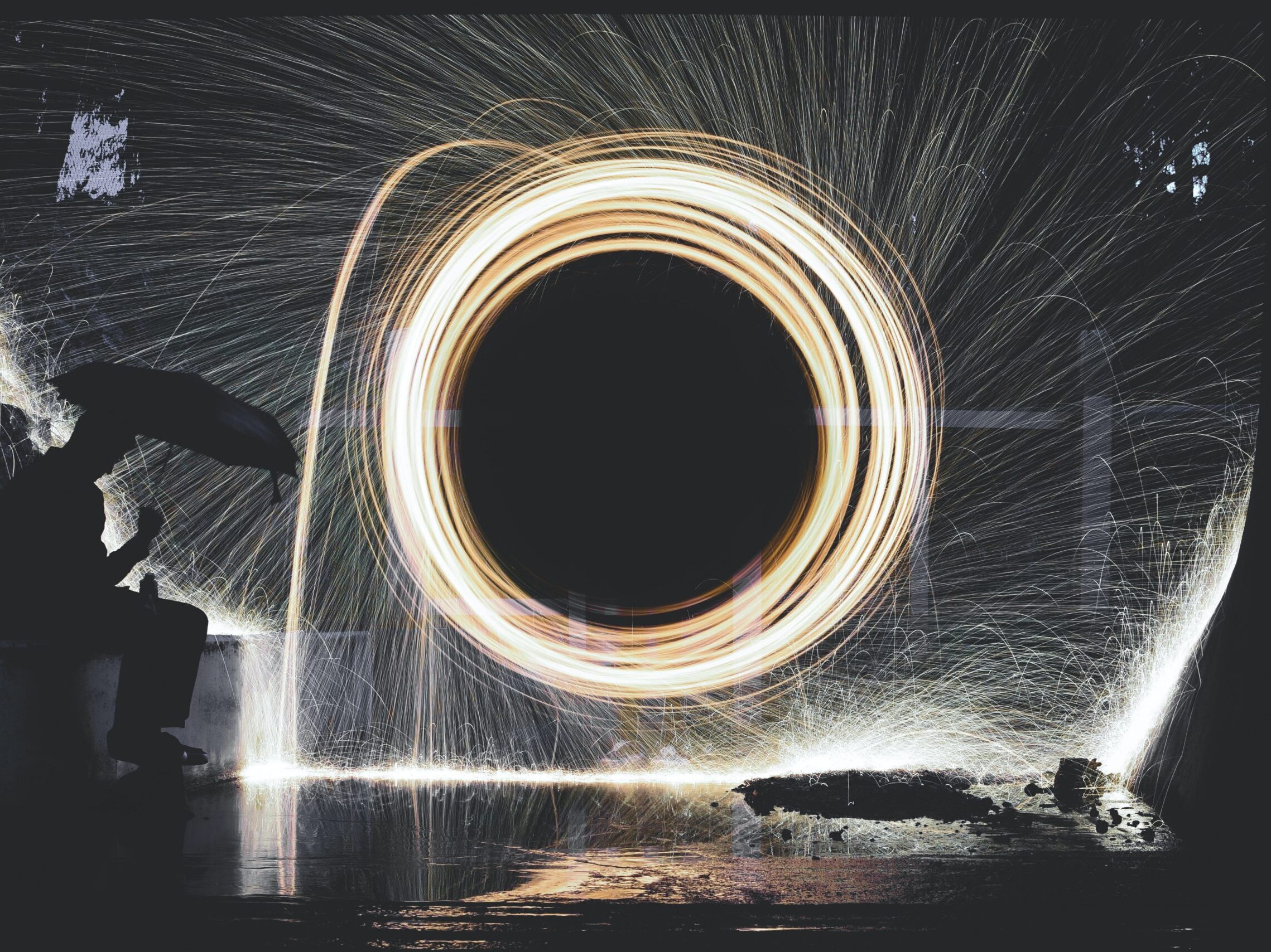 photo of person holding umbrella near steelwool during nighttime