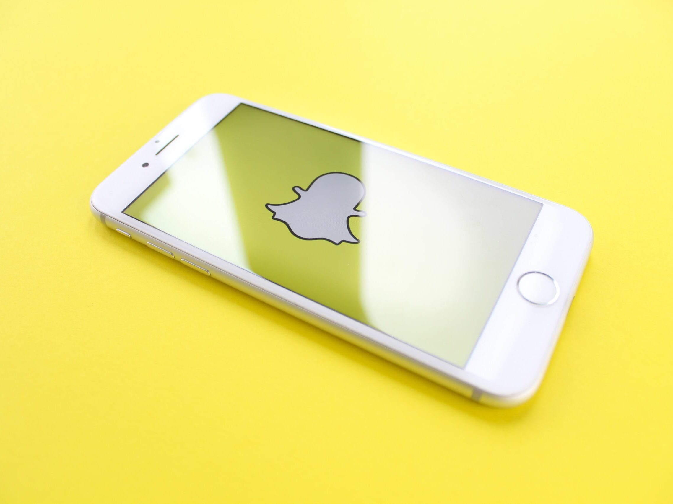 silver iPhone 6 on top of yellow wooden surface