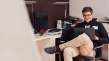 man smiling while sitting and using MacBook