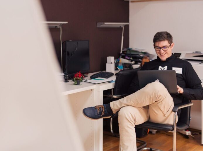 man smiling while sitting and using MacBook