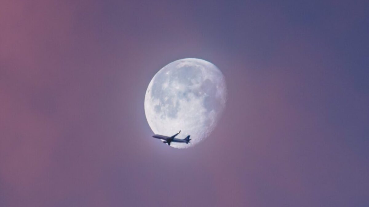 flying plane at sky during full moon at daytime