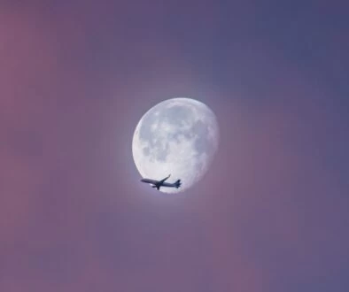 flying plane at sky during full moon at daytime