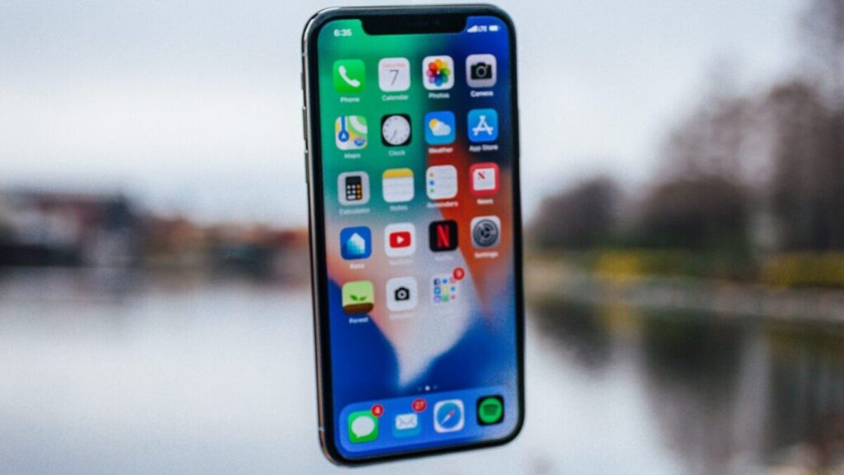 silver iPhone X floating over open palm