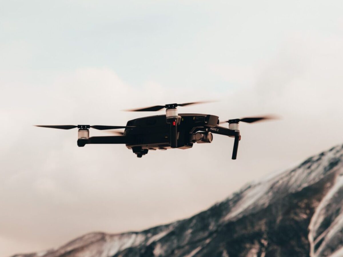 black drone flying over snow covered mountain