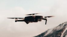 black drone flying over snow covered mountain