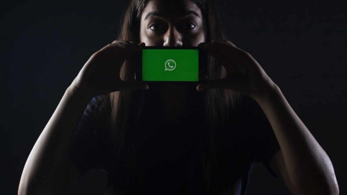 woman holding black smartphone at Whatsapp logo