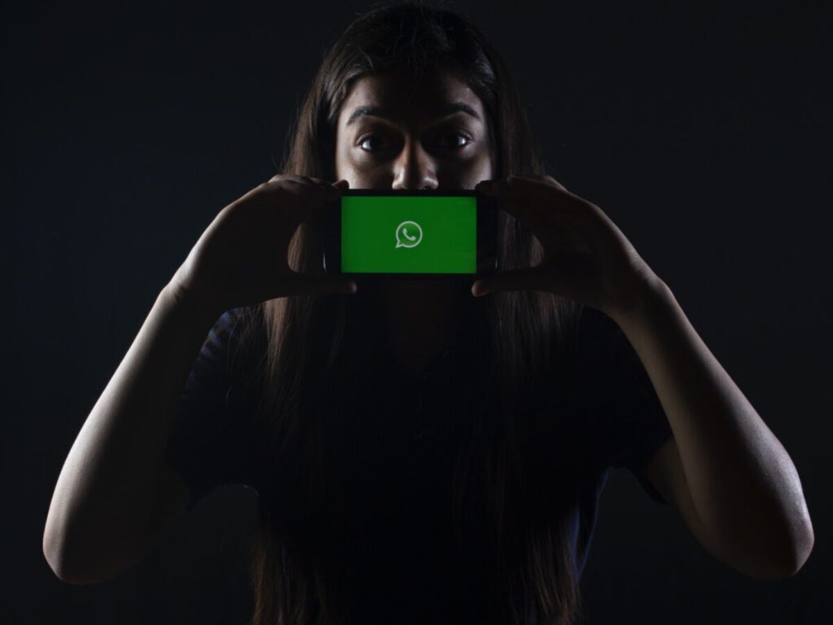woman holding black smartphone at Whatsapp logo