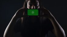 woman holding black smartphone at Whatsapp logo