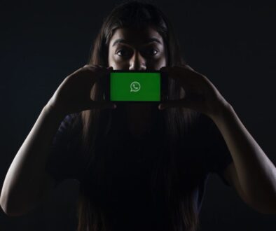 woman holding black smartphone at Whatsapp logo
