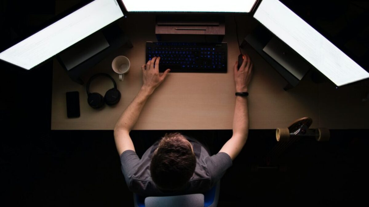 man facing three computer monitors while sitting