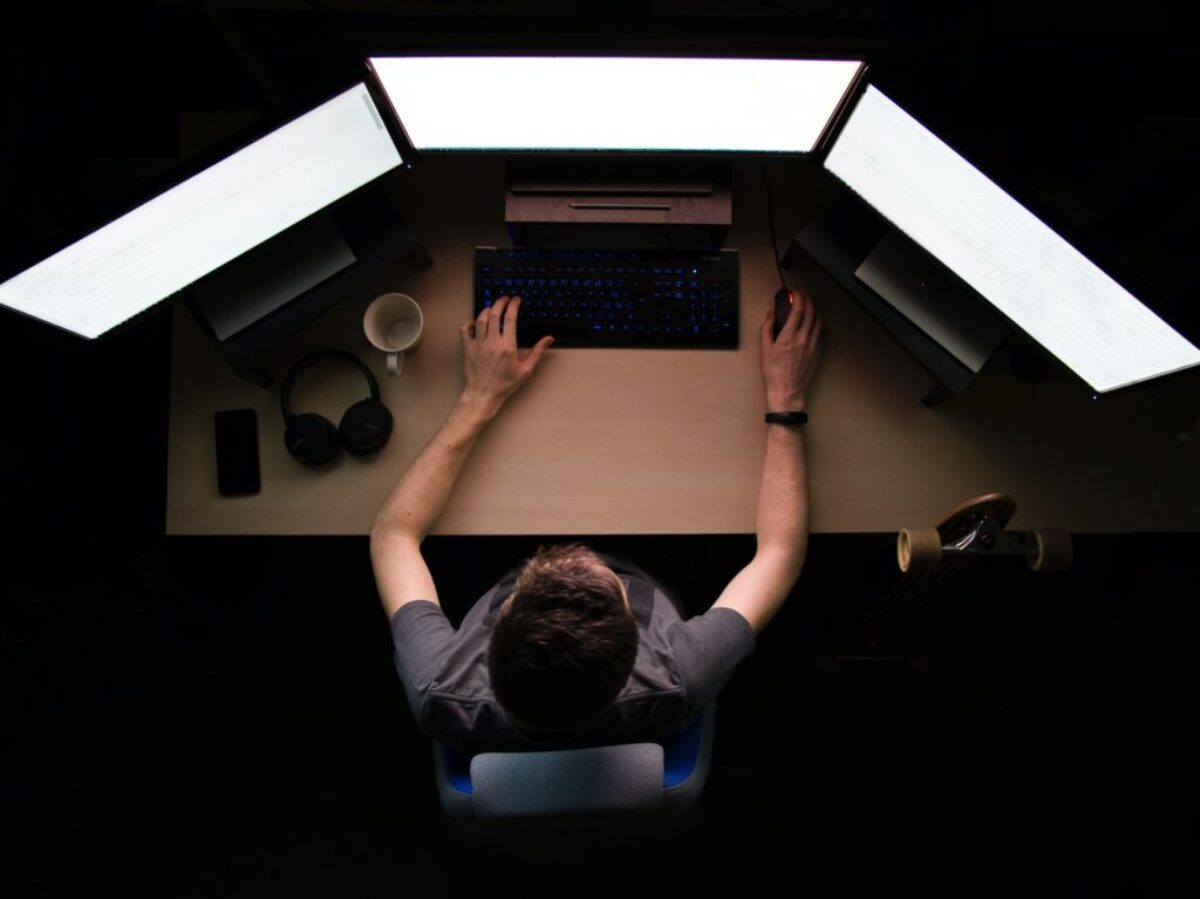 man facing three computer monitors while sitting