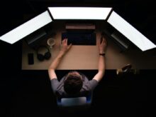 man facing three computer monitors while sitting