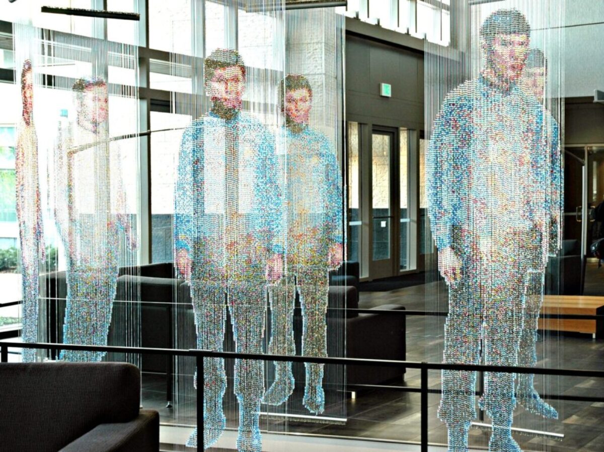 man in white and blue long sleeve shirt standing near glass window