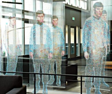 man in white and blue long sleeve shirt standing near glass window