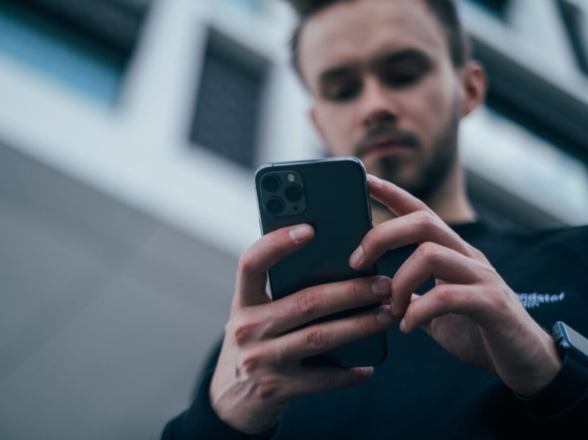 man wearing black sweater using smartphone