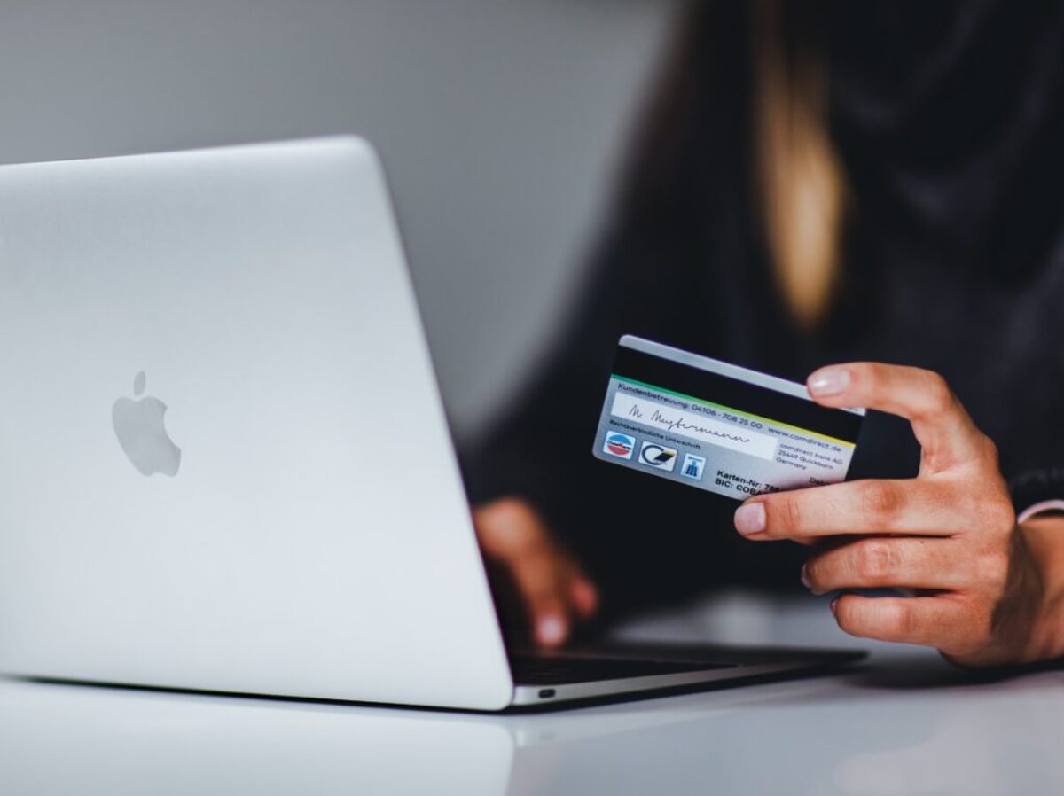 woman holding black smartphone near silver macbook