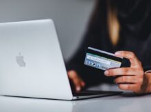 woman holding black smartphone near silver macbook