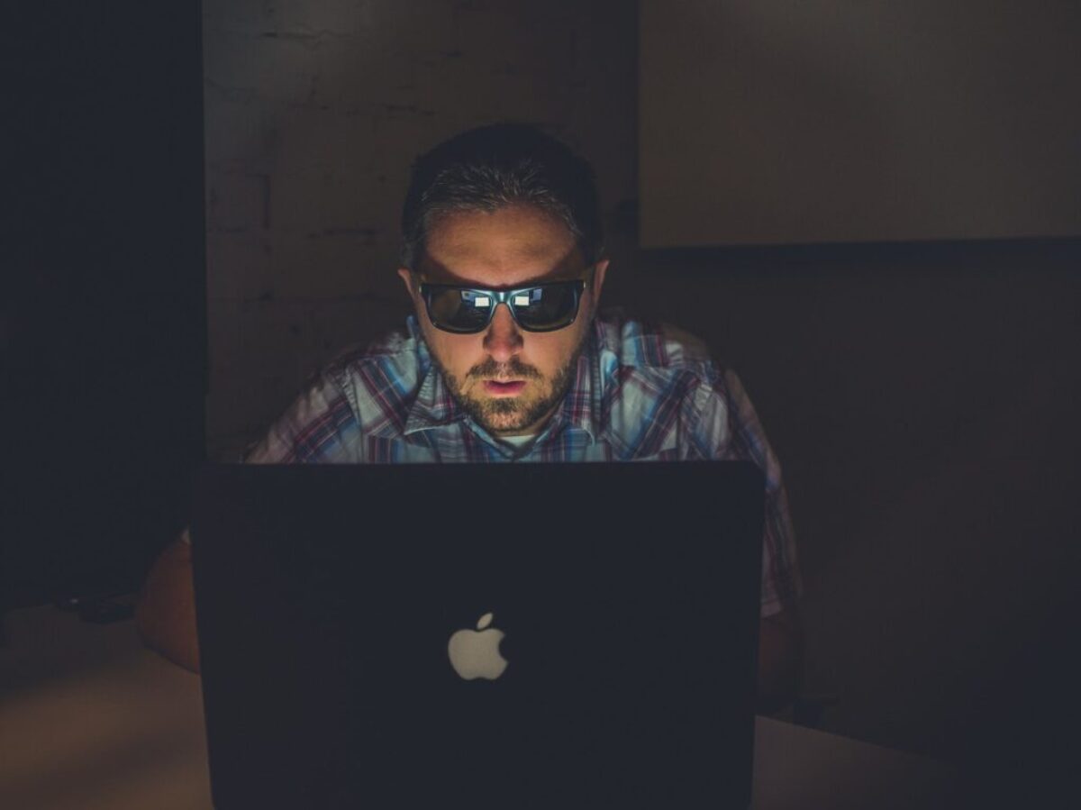 man wearing sunglasses using MacBook