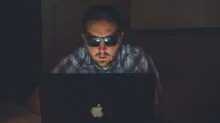 man wearing sunglasses using MacBook