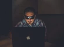man wearing sunglasses using MacBook