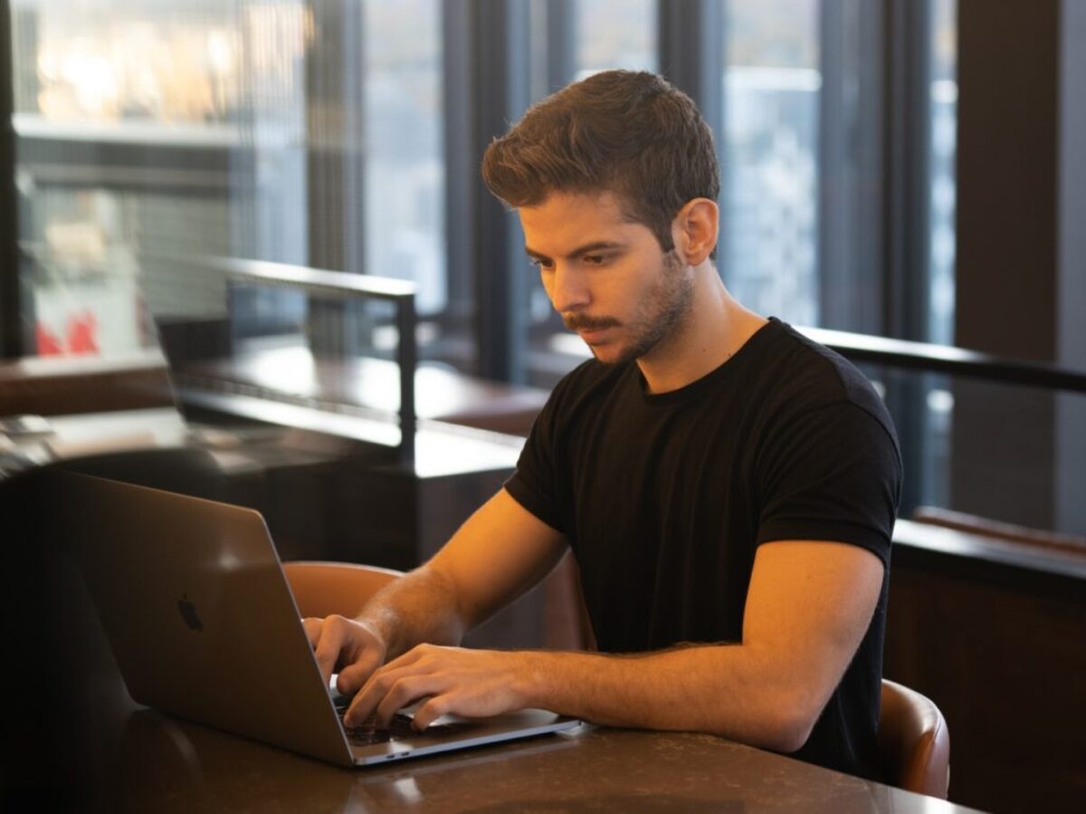 man in black crew neck t-shirt using macbook
