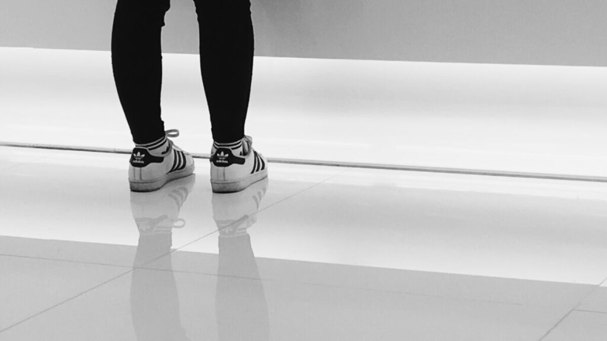 person wearing pair of white-and-black adidas running shoes