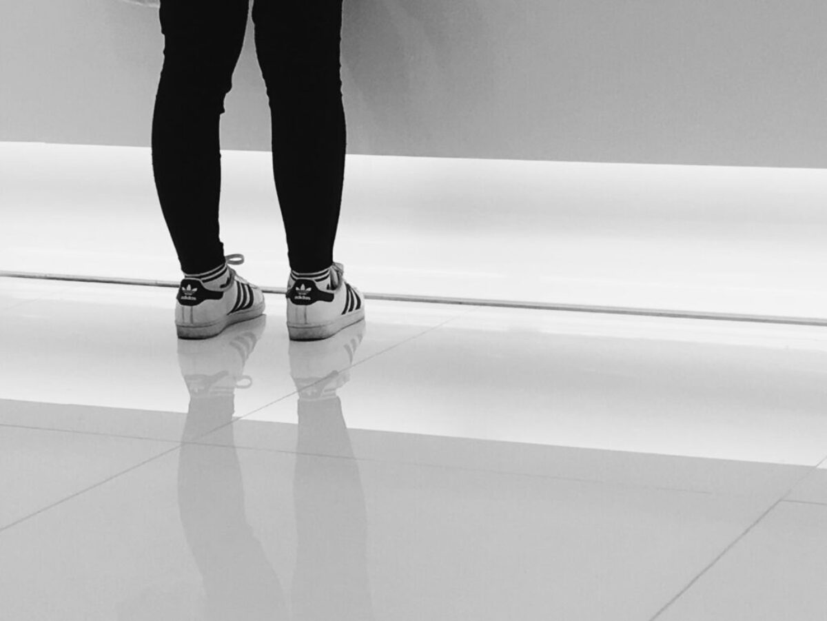 person wearing pair of white-and-black adidas running shoes