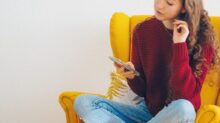 woman in red sweater and blue denim jeans sitting on yellow sofa chair