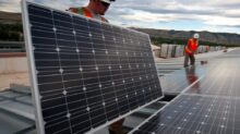 man in red shirt and black pants standing near solar panels during daytime