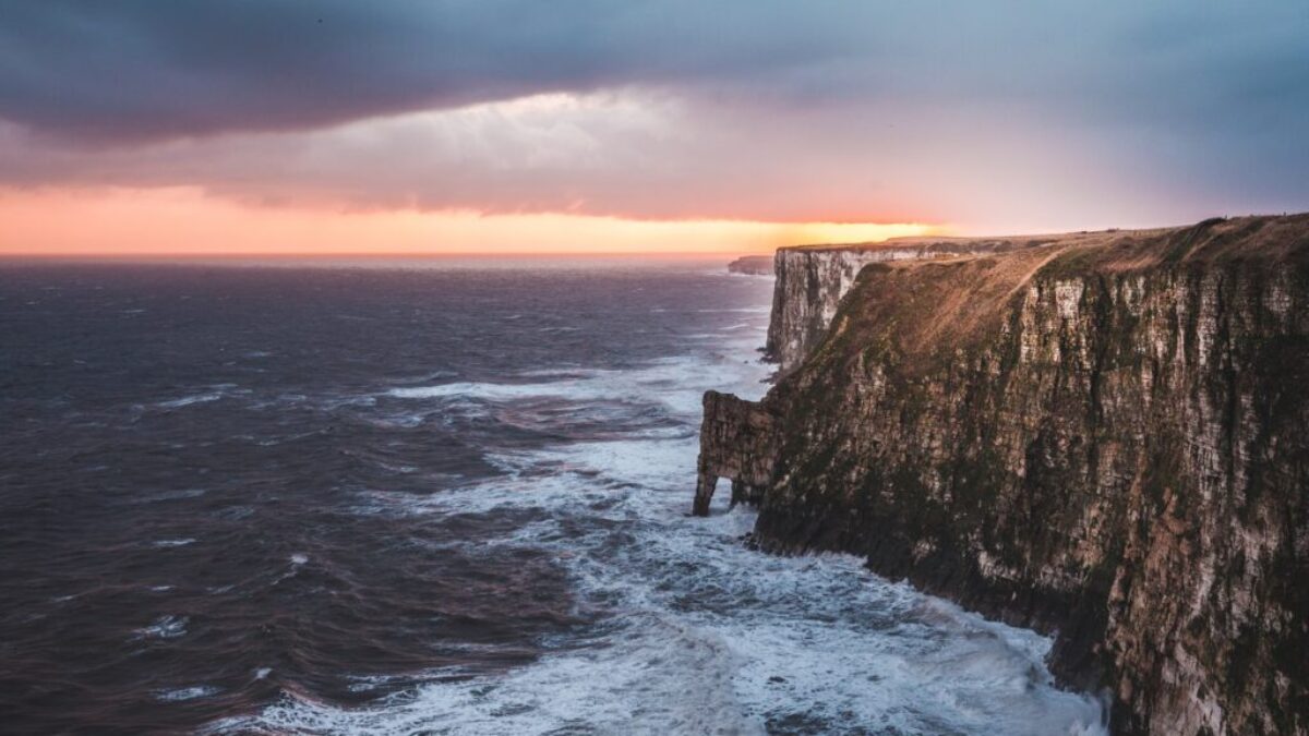 gray rocky mountain beside sea at golden hour