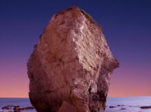 brown rock formation with body of water