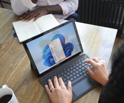 Overhead view of two people at a table working with a Microsoft laptop and notebook