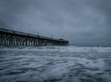 brown wooden dock on sea under white clouds