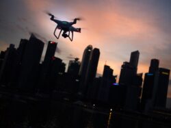 silhouette of quadcopter drone hovering near the city