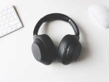 black wireless headphones between Apple Keyboard and Apple Magic Mouse on white surface