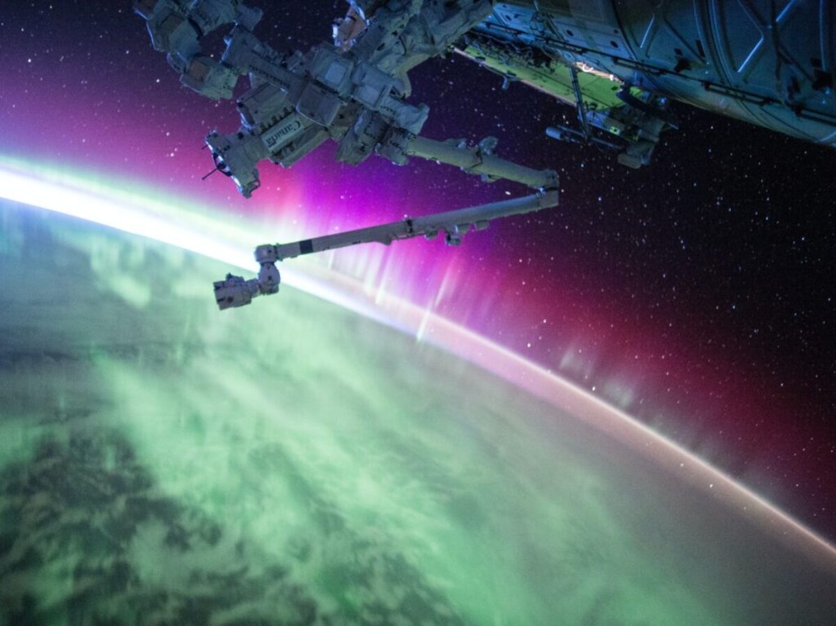 photography of purple and green aurora beam below grey space satellite