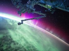 photography of purple and green aurora beam below grey space satellite
