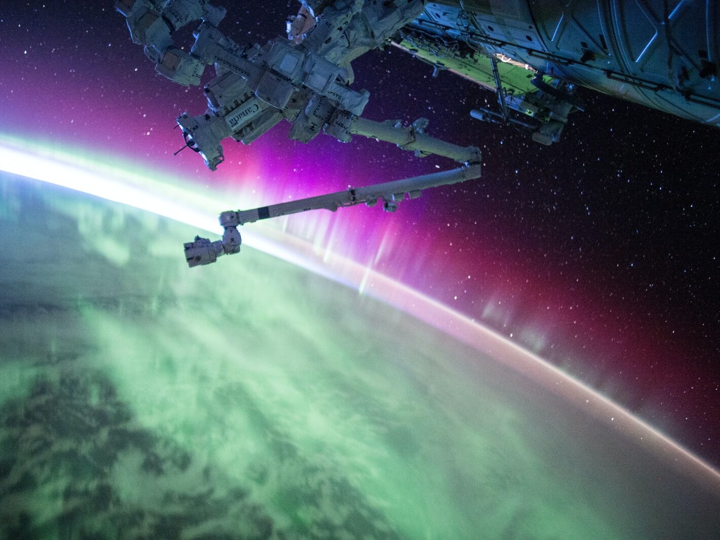 photography of purple and green aurora beam below grey space satellite