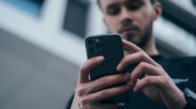 man wearing black sweater using smartphone