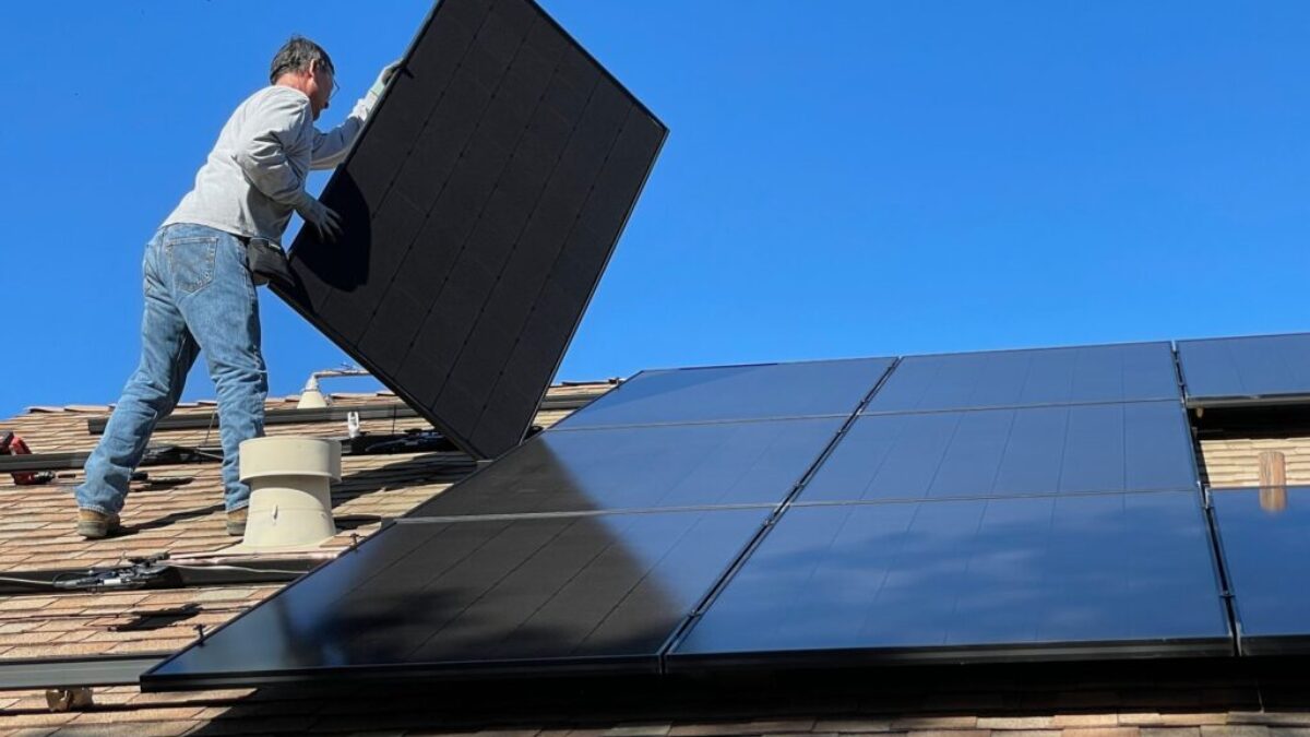 man in white dress shirt and blue denim jeans sitting on white and black solar panel