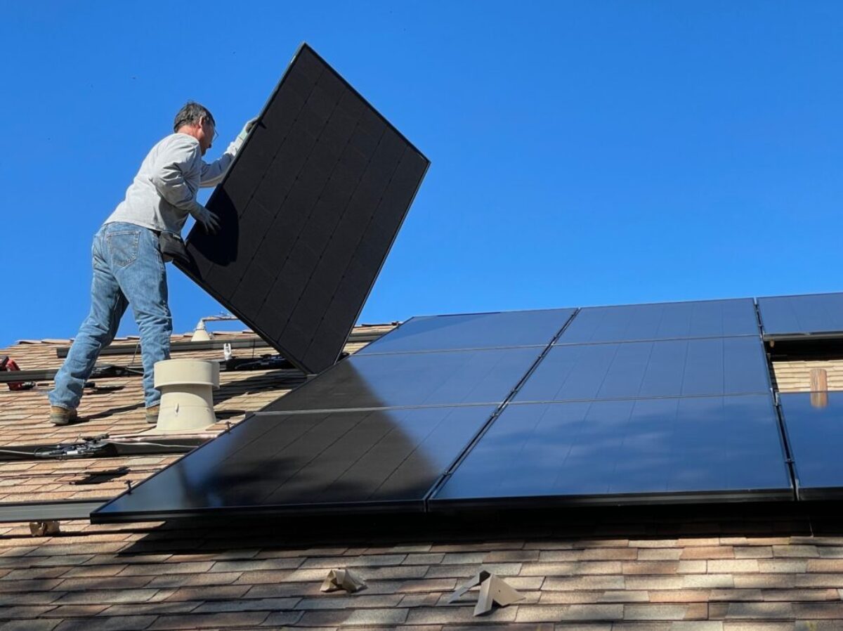 man in white dress shirt and blue denim jeans sitting on white and black solar panel