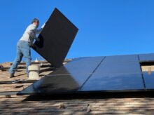 man in white dress shirt and blue denim jeans sitting on white and black solar panel