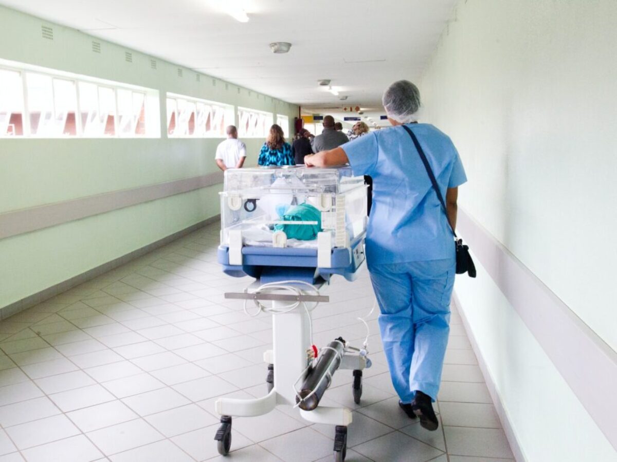 person walking on hallway in blue scrub suit near incubator