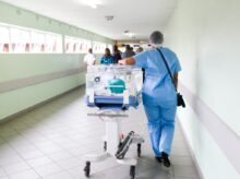 person walking on hallway in blue scrub suit near incubator