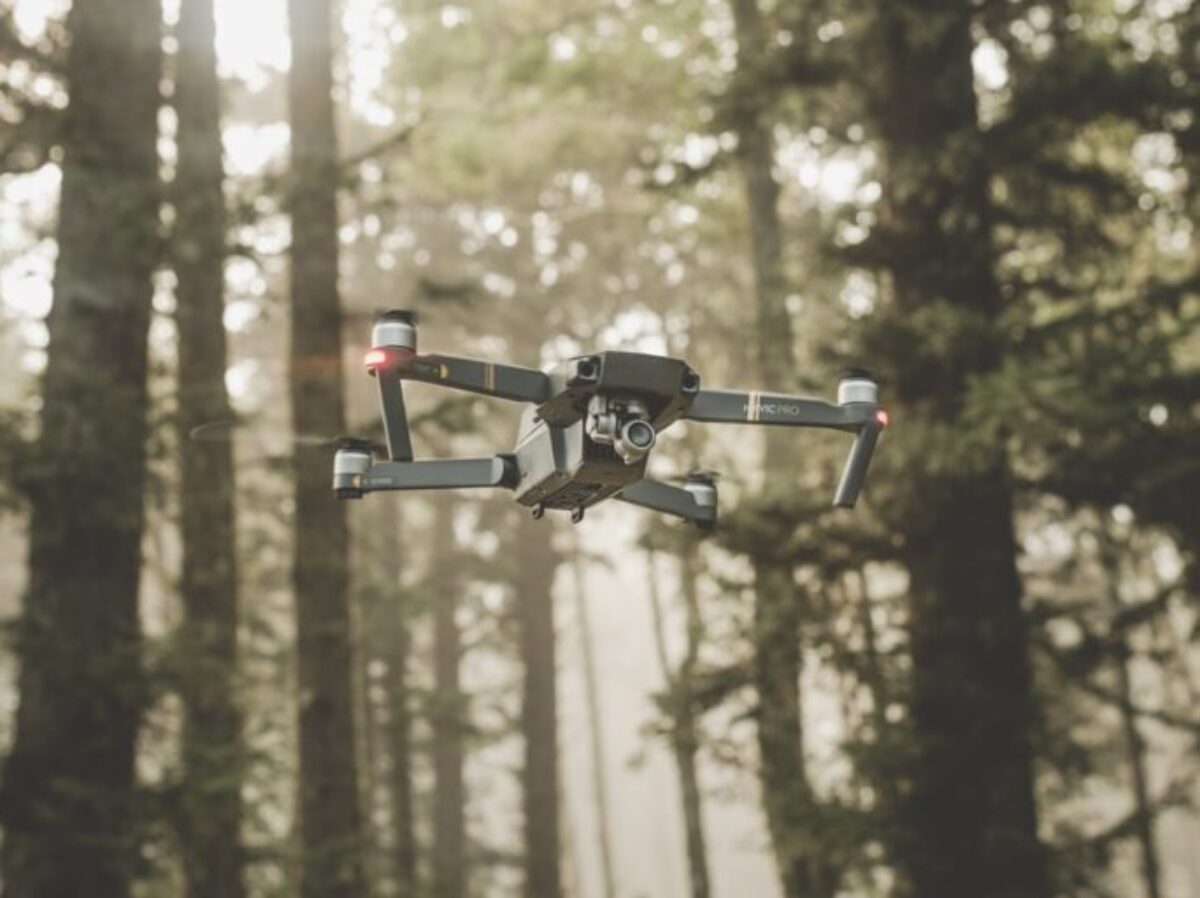 gray and black DJI Mavic Pro quadcopter drone on mid top air near forest at daytime