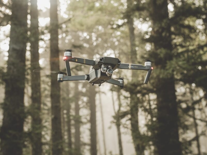 gray and black DJI Mavic Pro quadcopter drone on mid top air near forest at daytime