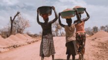 three women carrying basin while walking barefoot