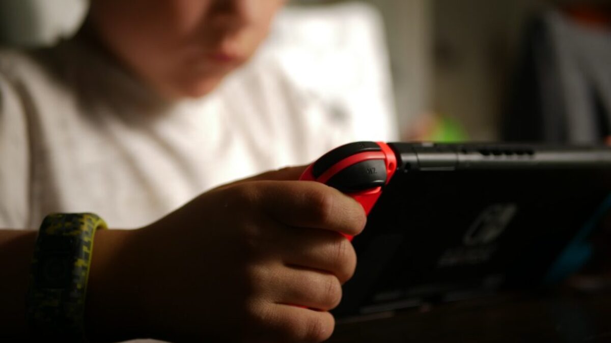 boy in white crew neck t-shirt holding black and red cordless device