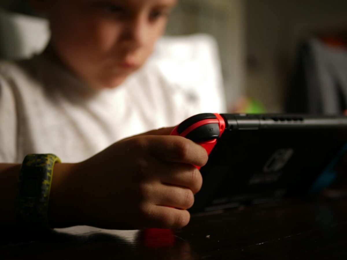 boy in white crew neck t-shirt holding black and red cordless device