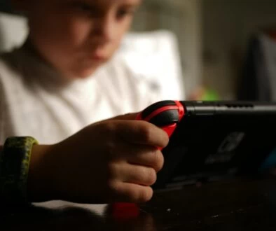 boy in white crew neck t-shirt holding black and red cordless device